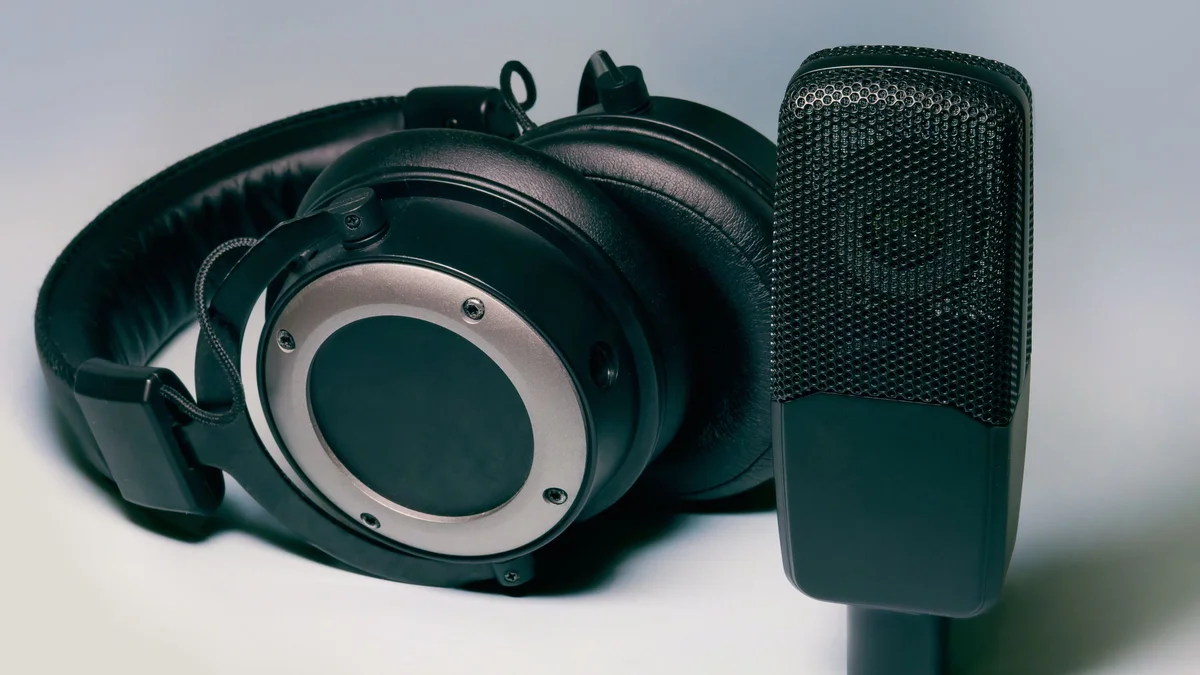 Studio audio headset and microphone placed side by side on light background