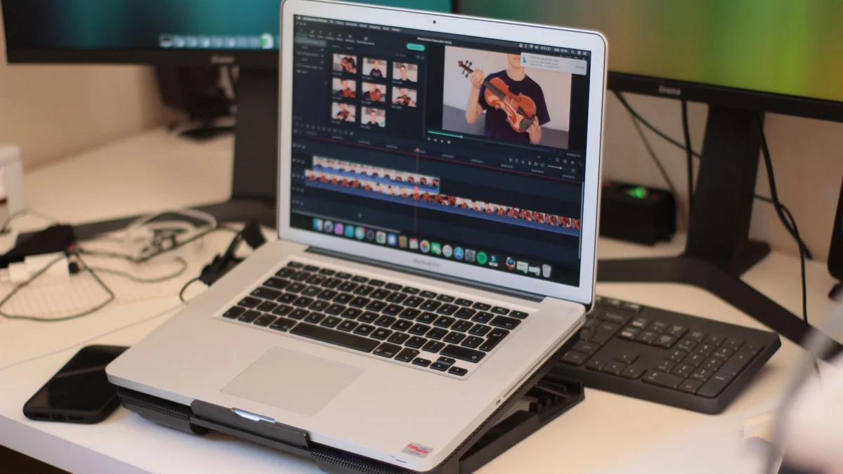 Ordinateur portable affichant un logiciel de montage vidéo sur un bureau avec clavier et écran externe
