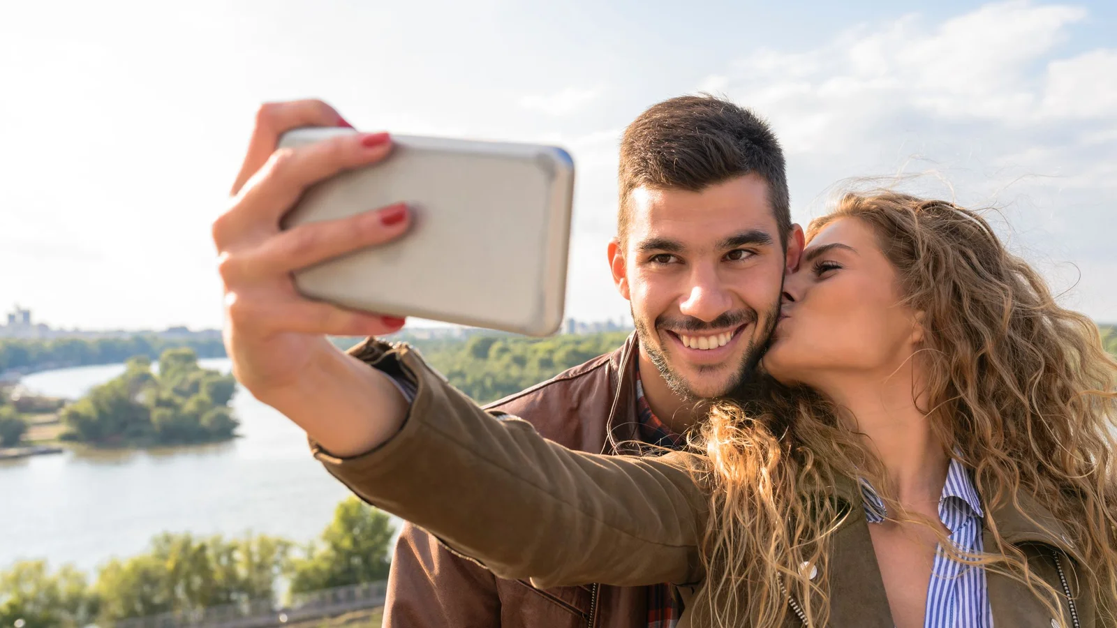 Couple prenant un selfie côte à côte au bord d'une rivière, exemple de photo de départ adaptée à un AI kiss