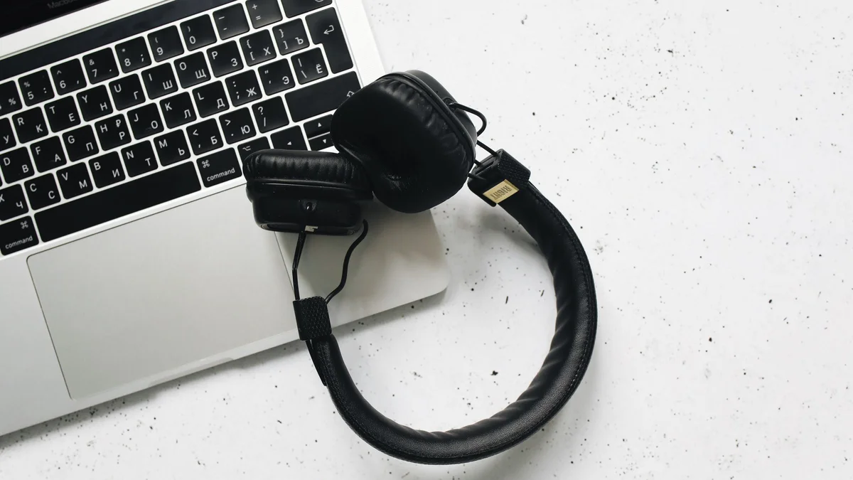 Ordinateur portable et casque audio posés sur un bureau, prêts pour une transcription